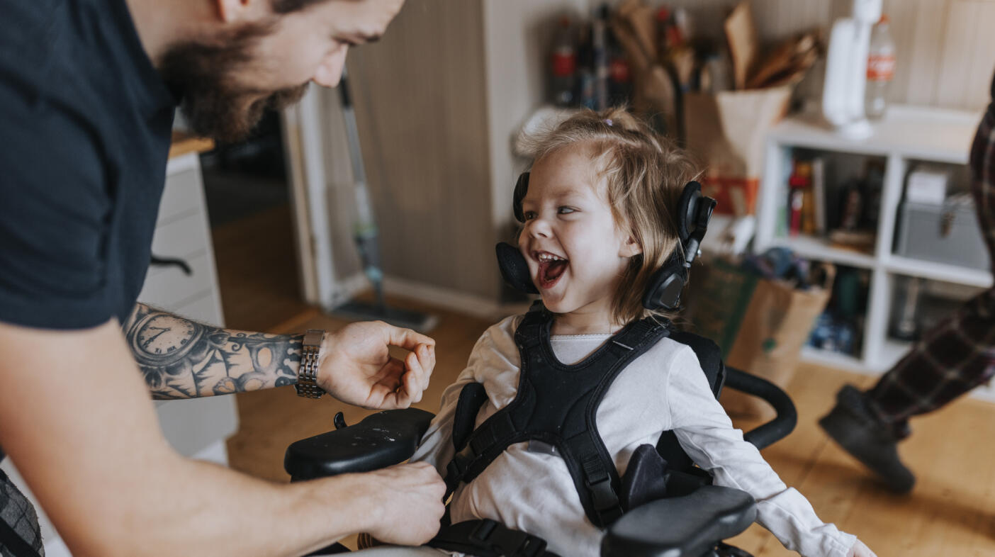 Father taking care of happy disabled child in wheelchair