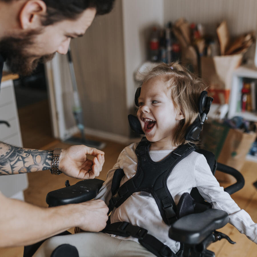 Father taking care of happy disabled child in wheelchair