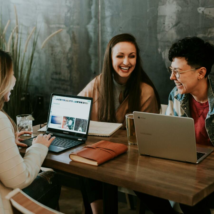 Three people sat in front of laptops and notebooks